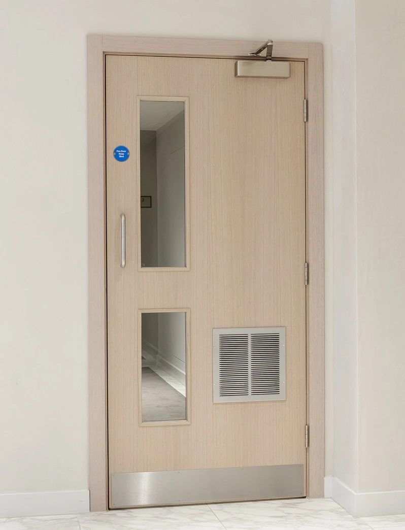 Fire door with closer, vision panels and intumescent grille in a corridor
